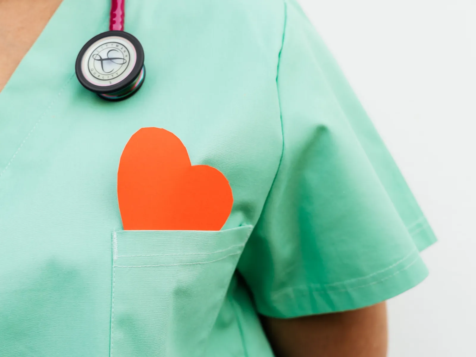 Primer plano de un corazón de papel naranja en el bolsillo del uniforme de una enfermera