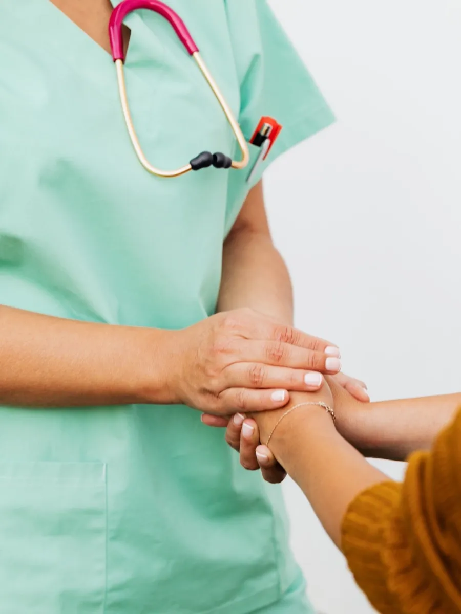 Profesional con uniforme sanitario sujetando con las dos manos la mano de un paciente