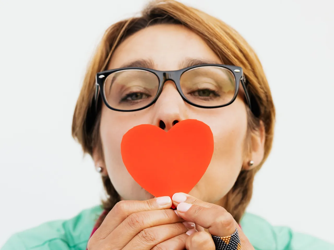 Profesional sosteniendo un corazón de papel coral con un gesto cariñoso