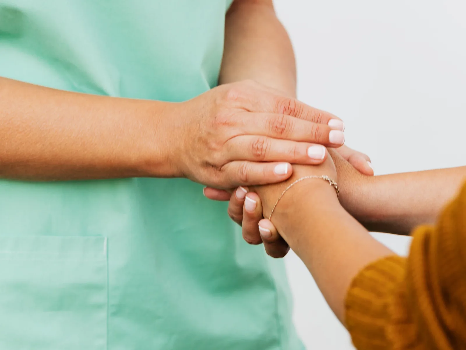 Profesional sanitaria sosteniendo con las dos manos la mano de una mujer